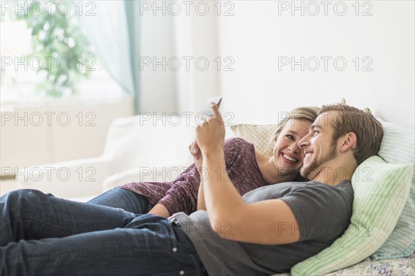 Smiling couple lying on bed and using digital tablet.