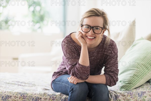 Portrait of smiling young woman sitting on bed.