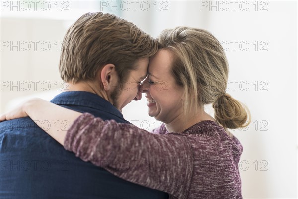 Close-up of smiling couple embracing.