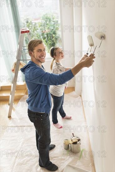 Smiling couple painting wall.