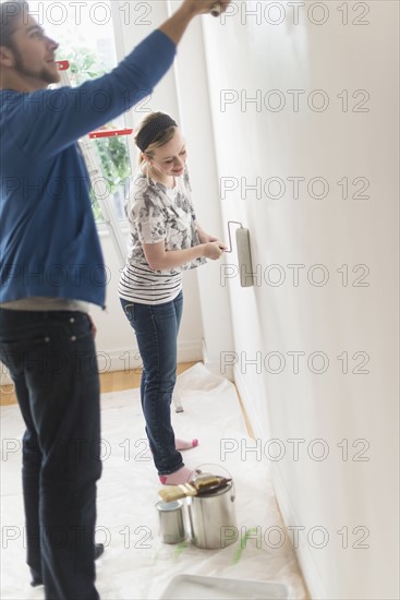 Smiling couple painting wall.