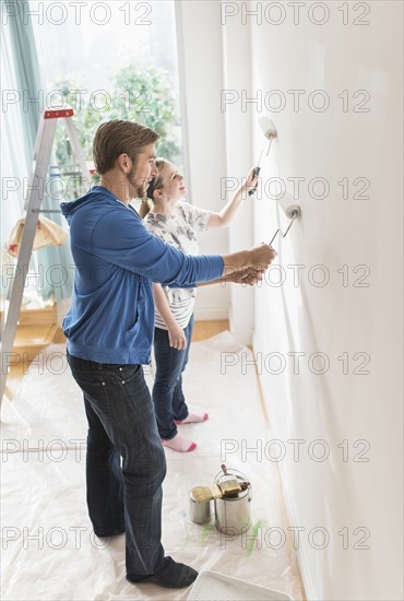 Smiling couple painting wall.