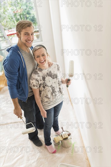 Portrait of smiling couple painting wall.
