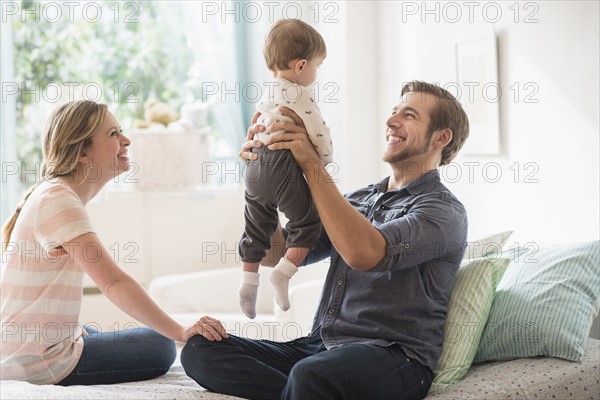 Happy parents playing with little son (2-3 years) on bed.