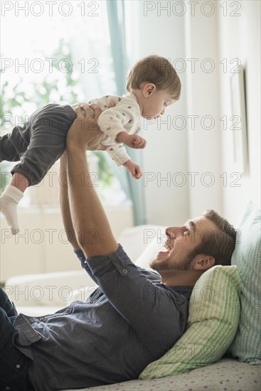 Happy father playing with little son (2-3 years) on bed.