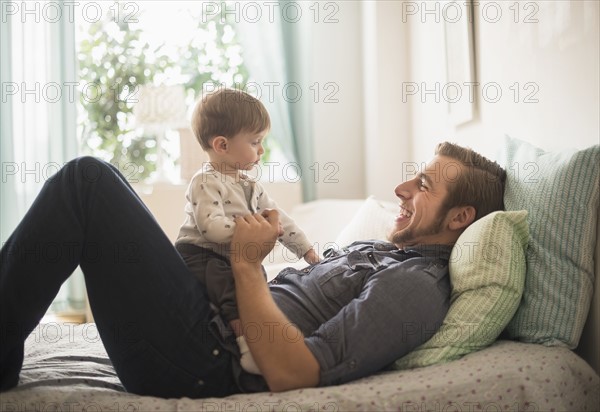 Happy father playing with little son (2-3 years) on bed.