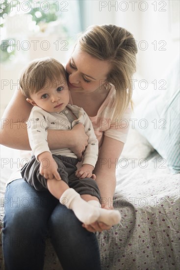 Mother sitting with little son (2-3 years) on bed.