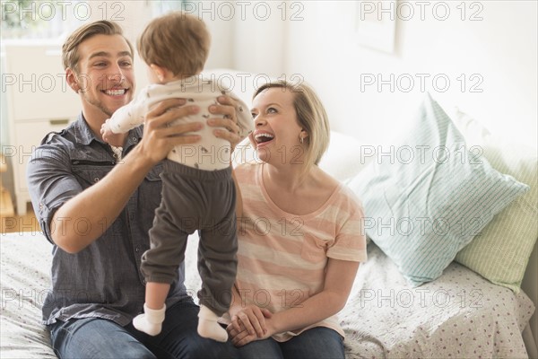 Happy parents playing with little son (2-3 years) on bed.