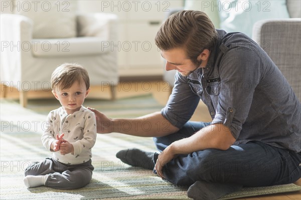 Father sitting on floor with little son (2-3 years).