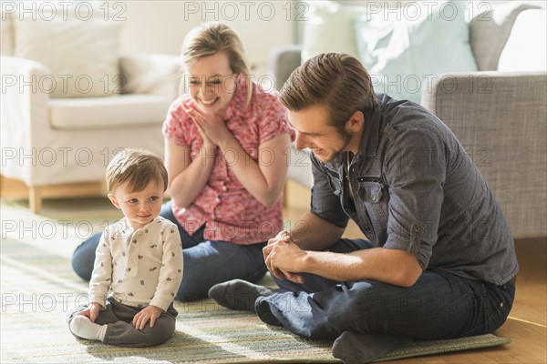 Happy parents sitting with little son (2-3 years) on floor.