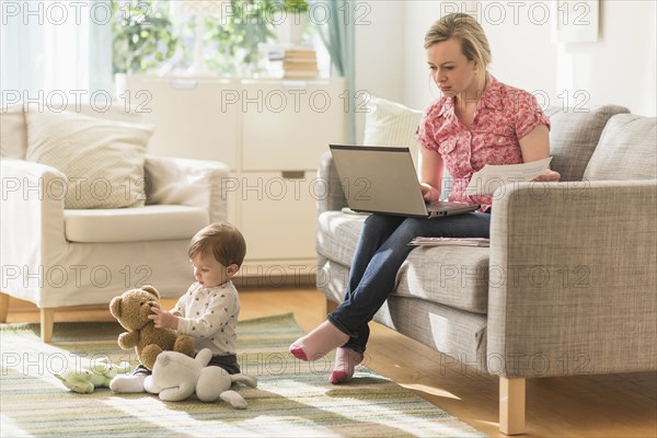 Working mother and son (2-3 years) in living room.