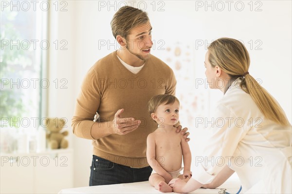 Small boy (2-3) with his father and female doctor in doctor's office.