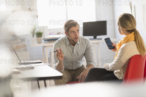 Young man and woman discussing at desk in office.