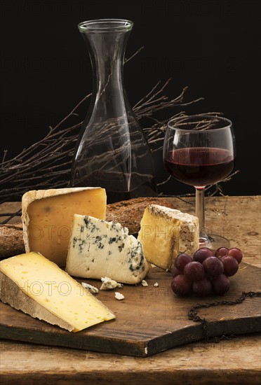 Still life with cheese and red wine on wooden table, studio shot.