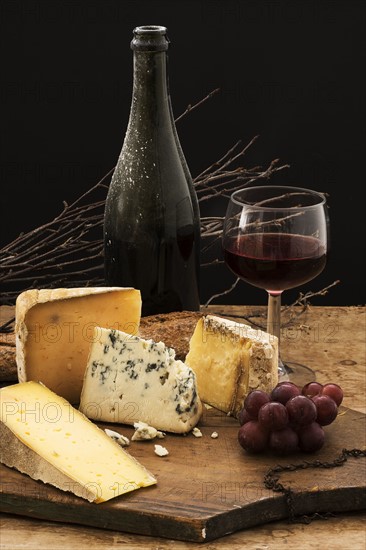 Still life with cheese and red wine on wooden table, studio shot.