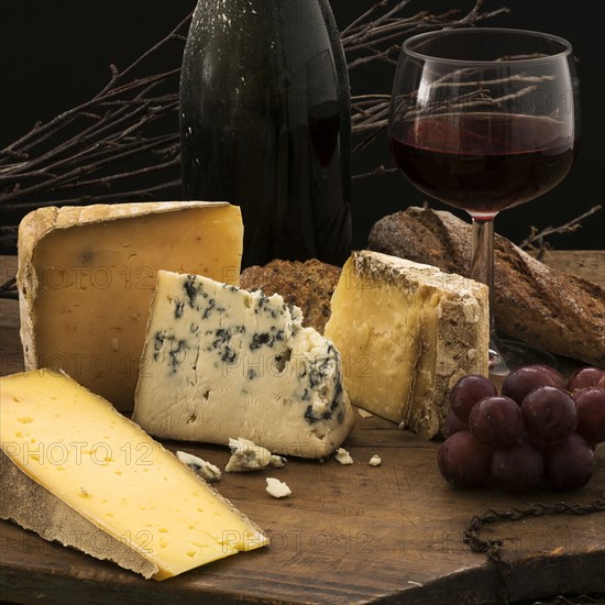 Still life with cheese and red wine on wooden table, studio shot.