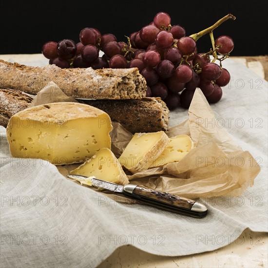 Still life with grapes and cheese and bread slices on wooden table, studio shot.