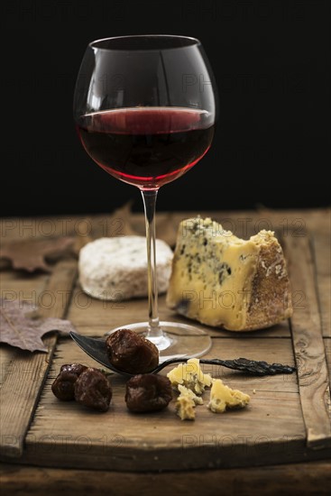 Still life with cheese and red wine on wooden table, studio shot.