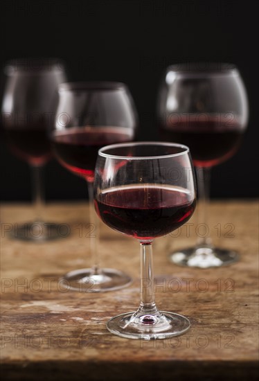 Red wine in glasses on wooden table, studio shot.