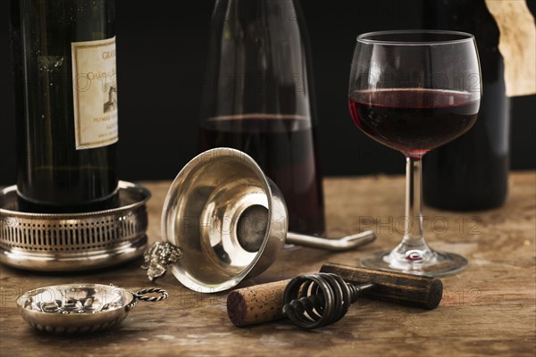 Still life with red wine glass, carafe and bottle on wooden table, studio shot.