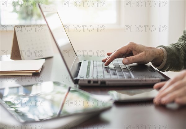 Close up of man's hands using laptop at desk.