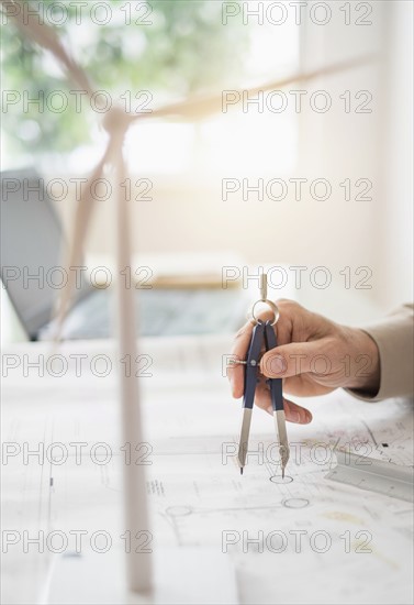 Close up of man's hands using compass while drawing plans.