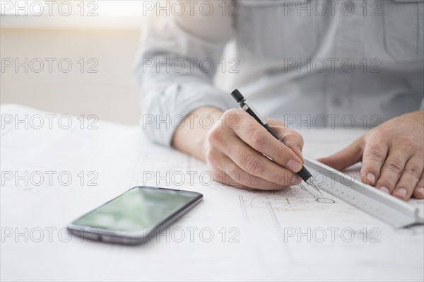 Close up of architect's hands drawing on blueprint.