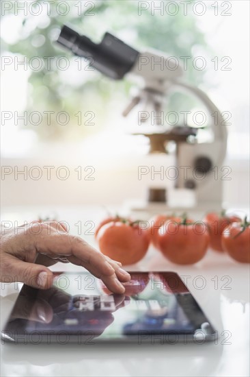 Close up of man's hand using digital tablet in laboratory.