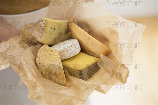 Close up of man's hand holding slices of cheese in paper.