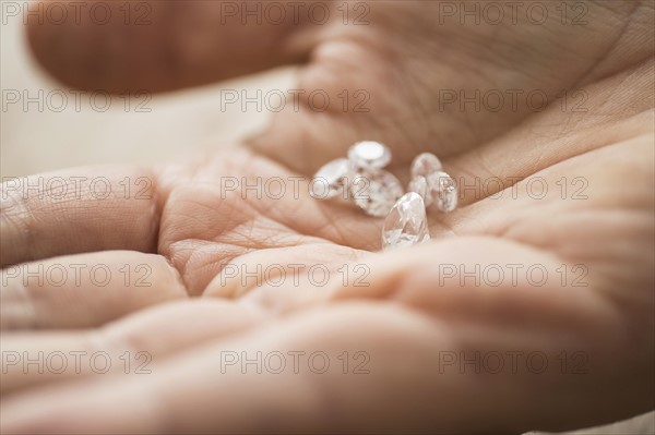 Close up of man's hand holding diamonds.