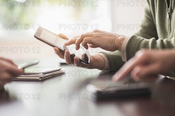 Close up of hands of men and woman working with electronical devices.