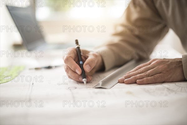 Close up of architect's hands drawing on blueprint.