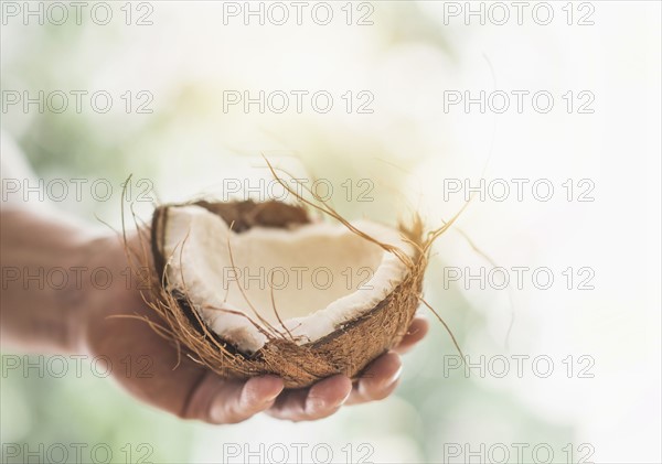 Close up of man's hand holding part of coconut.