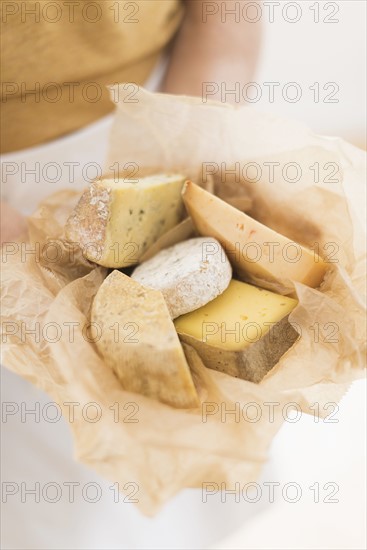 Close up of man's hand holding slices of cheese in paper.