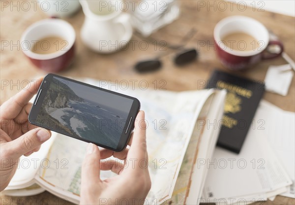 Close up of man's hand holding smartphone above map.