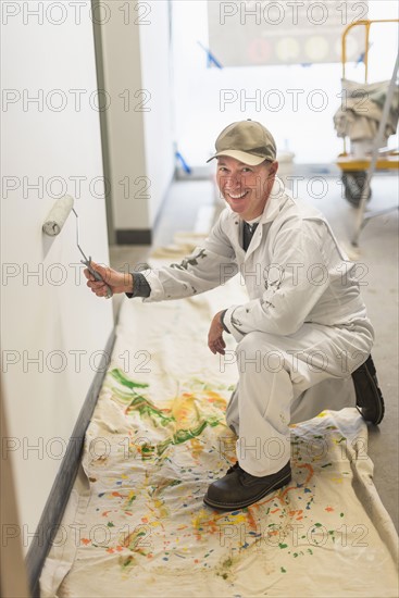Portrait of smiling manual worker painting wall.