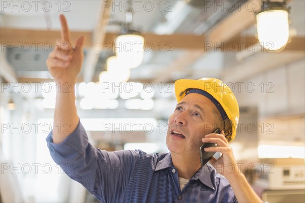 Architect in hardhat talking on mobile phone.