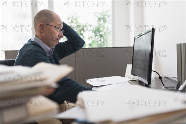 Surprised mature businessman looking at computer monitor .