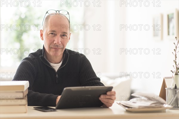 Portrait of mature man working in home office .