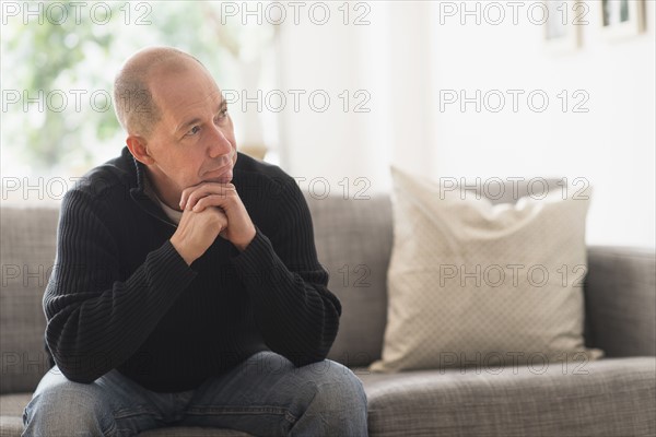 Portrait of mature man relaxing on sofa in living room .