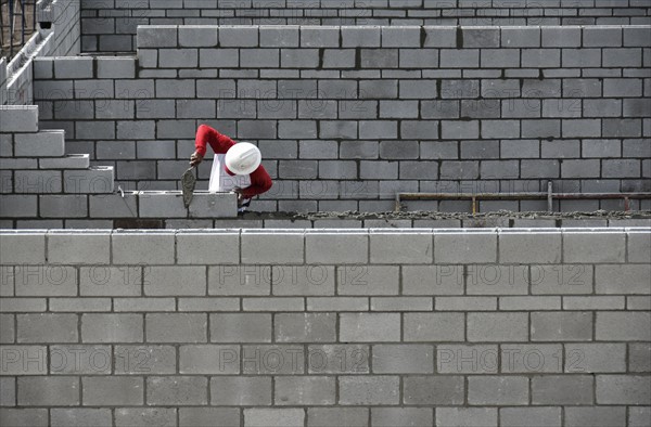 Bricklayer working on brick wall.