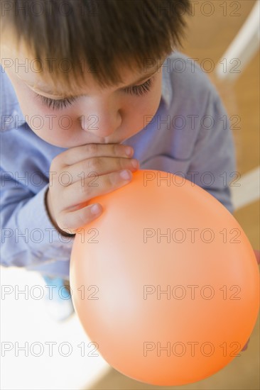Boy (6-7) inflating balloon