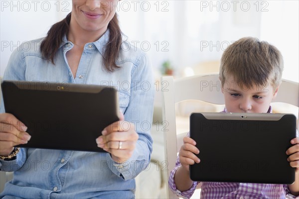 Mother and son (6-7) using digital tablet
