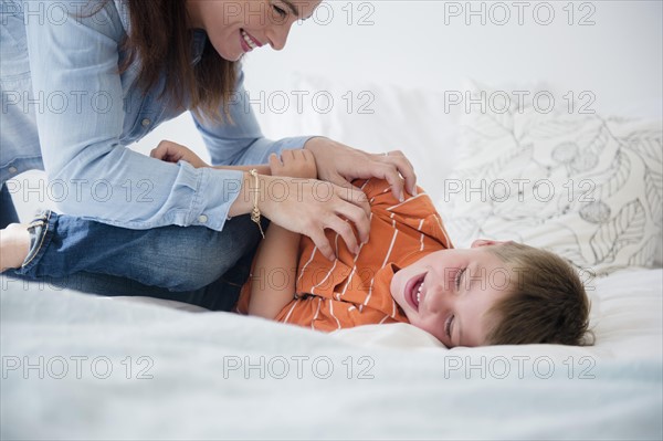 Mother and son (6-7) playing in bed