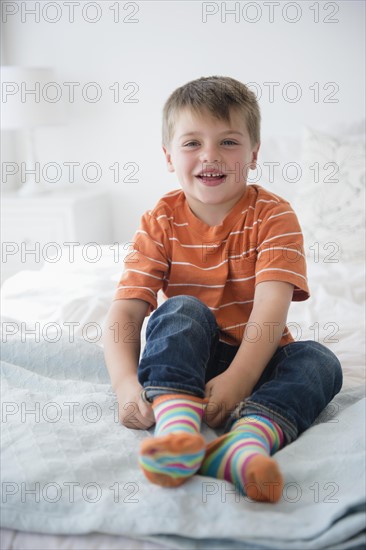 Portrait of boy (6-7) sitting on bed