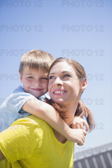 Mother giving her son (6-7) piggyback ride
