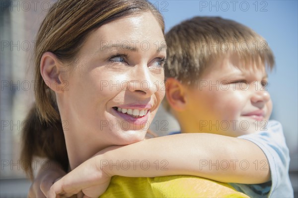 Mother giving her son (6-7) piggyback ride