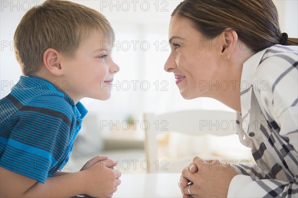 Mother and son (6-7) facing each other in domestic room