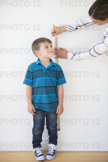 Mother measuring son (6-7) with ruler