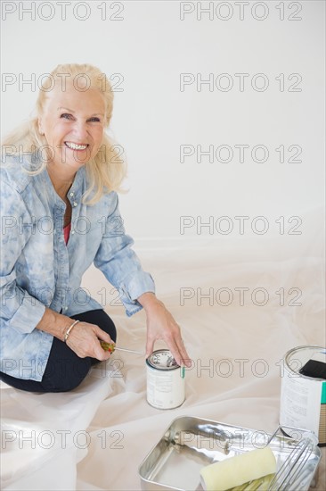 Portrait of senior woman opening paint can